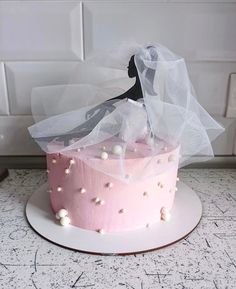 a pink cake with white frosting and a veil on top