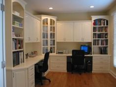 a home office with white cabinets and wood flooring in the middle of an empty room