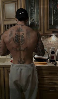 a man with tattoos on his back standing in front of a sink