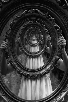 the reflection of a woman's face in a circular mirror, with her hands holding it