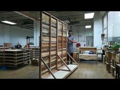 a man standing next to a wooden wall in a room filled with boxes and shelves