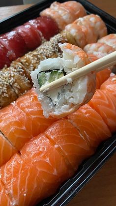 sushi is being served in a tray with chopsticks