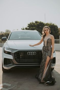 a woman standing next to an audi car