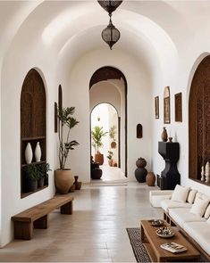 a living room filled with white furniture and lots of potted plants on the wall