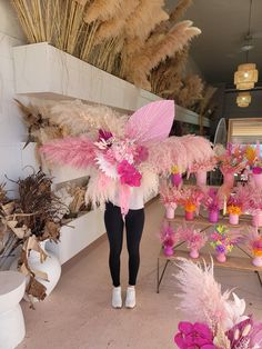 a woman is standing in front of some flowers and feathers