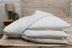 three pillows stacked on top of each other on a bed in front of a wooden headboard