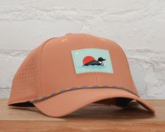 Get ready to make a statement with our Dogwood Snapback. It's orange and has a perforated fabric back, this hat is perfect for any occasion. But what really sets it apart is the new 'loon' rubber patch and funky rope accessory. So go ahead, stand out from the crowd and add a little fun to your wardrobe. - 97% Cotton 3% Spandex - One size - Spot clean recommended - Designed in Minnesota - Imported Retail: $30 Orange Adjustable Baseball Cap With Curved Brim, Orange Adjustable Curved Brim Baseball Cap, Orange Curved Brim Hat For Outdoor, Orange 5-panel Hat For Outdoor, Adjustable Orange Hat With Curved Bill, Orange Curved Brim Sports Hat, Rubber Patch, Kids Jewelry, Go Ahead