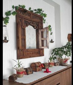 a wooden mirror sitting on top of a table next to potted plants and other items