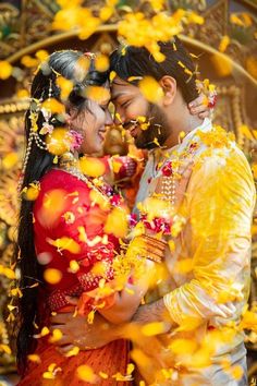 a man and woman standing next to each other in front of yellow flowers on the ground