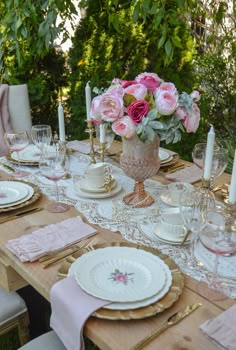 the table is set with pink flowers and white dishes