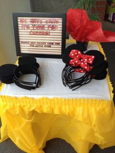 mickey mouse ears and headbands are on display at the table with a sign