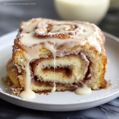 a cinnamon roll with icing on a white plate