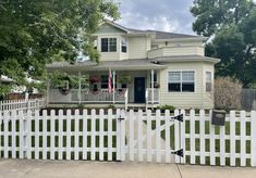 a white picket fence in front of a house with an american flag hanging on it