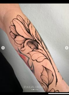 a woman's arm with black ink and flowers on the inside of her arm