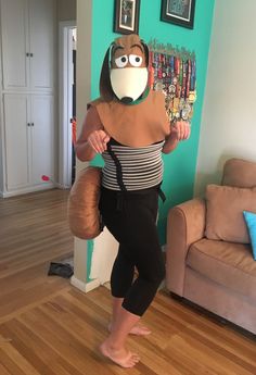 a woman standing in front of a wall with an owl mask on her head and leggings