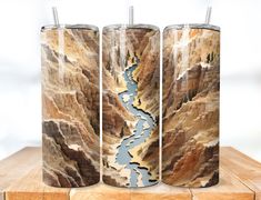 three tall vases sitting on top of a wooden table filled with water and rocks