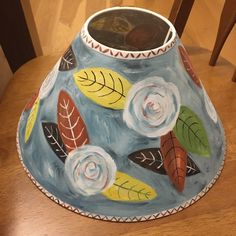 a painted lamp shade sitting on top of a wooden table