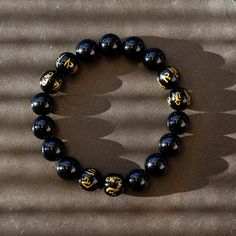 This is a mystical crystal beaded Mala bracelet, with the fusion of black onyx with the power of a Tibetan Buddhist Symbols -- 6 of the onyx beads are engraved the golden symbols! It gives the Peace, the Power, and the Protection to the person who wear it. Size(this brace let comes in 3 sizes, please select carefully):Size(this brace let comes in 3 sizes, please select carefully): -----Small: Bead diameter: 3/8 inch (10 mm) Bracelet circumference: 6 inch (15 cm) -----Medium: Bead diameter: 1/2 i Spiritual Onyx Beaded Bracelets, Black Spiritual Beaded Jewelry, Adjustable Black Wristband With Gemstone Beads, Adjustable Black Beaded Bracelets With Polished Beads, Black Gemstone Round Beads, Black Round Gemstone Beads, Spiritual Obsidian Jewelry With Black Beads, Adjustable Black Gemstone Beaded Bracelets, Spiritual Obsidian Black Beads Jewelry