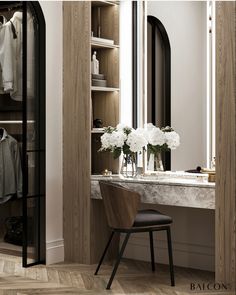 a room with a desk, mirror and chair next to a shelf full of clothes