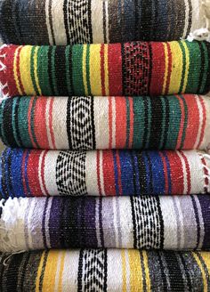 a stack of towels sitting on top of each other in front of a pile of rugs