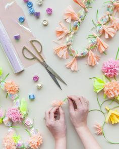 a woman is making flowers out of paper and beads on the table next to scissors