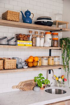 a kitchen with open shelving filled with lots of food and plants next to a sink