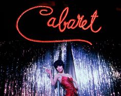 a woman in a red dress standing under a neon sign that says cabret on it