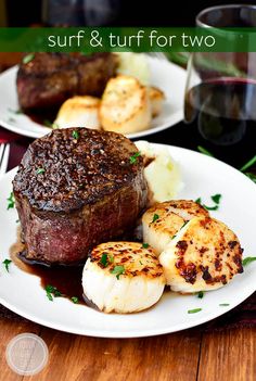 steak and scallops are served on two white plates