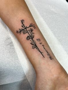 a woman's arm with a cross and flowers tattooed on the side of it