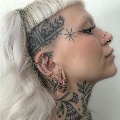 a woman with tattoos on her face and ear