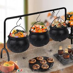 three black caulders filled with halloween treats on top of a table covered in candy