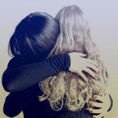 two women hugging each other with their arms wrapped around them and one woman's hair is curled back