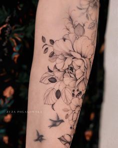 a woman's arm with flowers and birds tattoo on her left arm, which is black and white