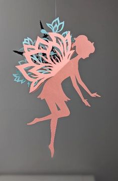 a paper cut out of a fairy with flowers in her hair hanging from a string