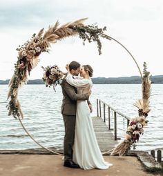 a bride and groom kissing in front of the water at their wedding ceremony on a dock