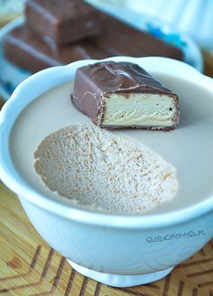 two pieces of cake in a white bowl on a wooden table next to chocolate and marshmallows