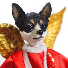 a small dog wearing a red and gold outfit with wings on it's back