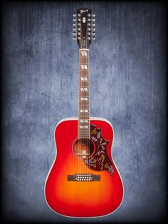 a red acoustic guitar sitting on top of a blue wall