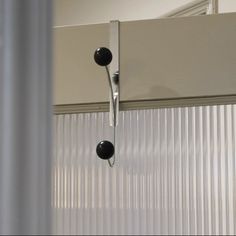 two black knobs are attached to the side of a white door with vertical blinds