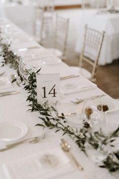 the table is set with white linens and place settings for guests to sit at