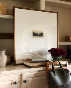 a vase filled with flowers sitting on top of a counter next to a framed photograph