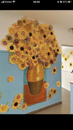 a vase filled with lots of yellow sunflowers on top of a blue wall