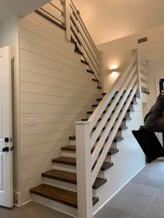 a man sitting on top of a chair next to a stair case in a living room