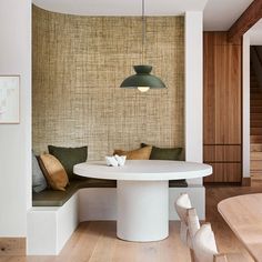 a white table sitting under a green light in a room with wooden floors and walls