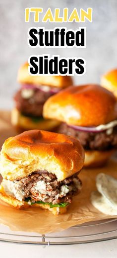 two hamburger sliders sitting on top of a wooden cutting board with the words italian stuffed sliders above them