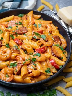 a skillet filled with pasta and meat on top of a table next to cheese