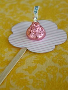 a piece of candy sitting on top of a paper plate next to a wooden stick