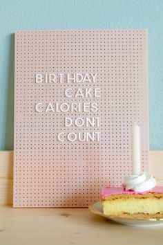 a piece of cake sitting on top of a plate next to a sign that says, birthday cake calories don't count