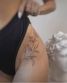 a woman is getting her tattoo done on her thigh with flowers in the back and behind her