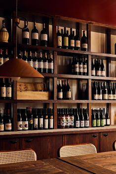 a wooden table sitting next to a shelf filled with lots of bottles and wine glasses